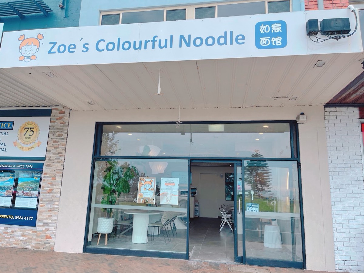 The shopfront in daylight, with a blue "Zoe's Colourful Noodle" sign over big glass doors and windows